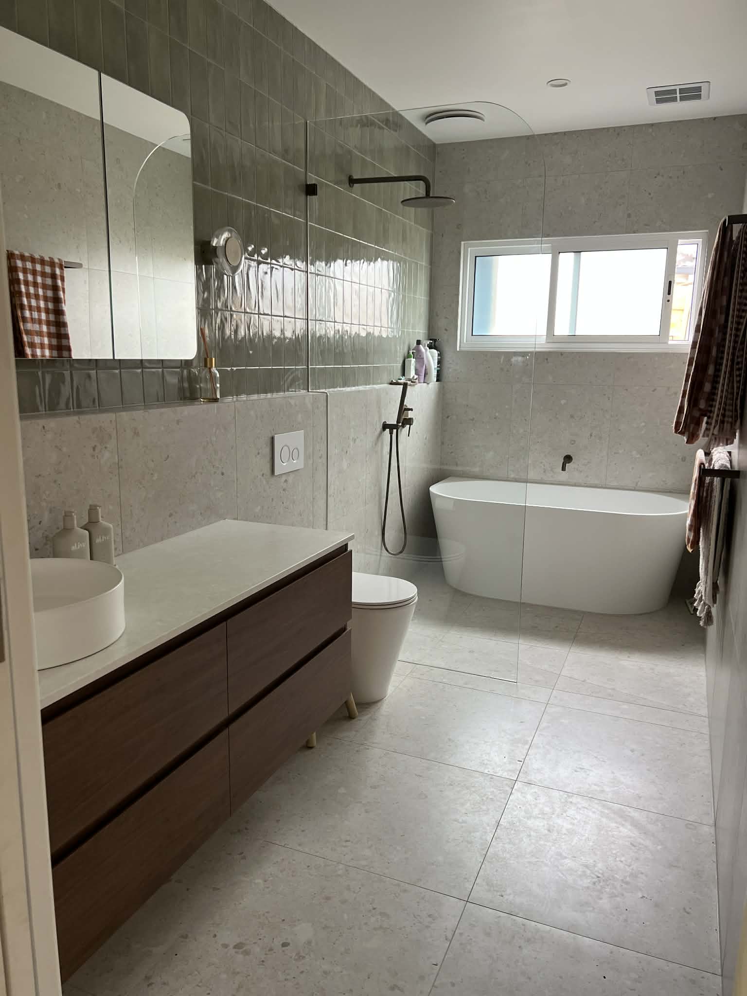 Renovated bathroom with grey terrazzo tile, freestanding bath, timber vanity and vessel sink